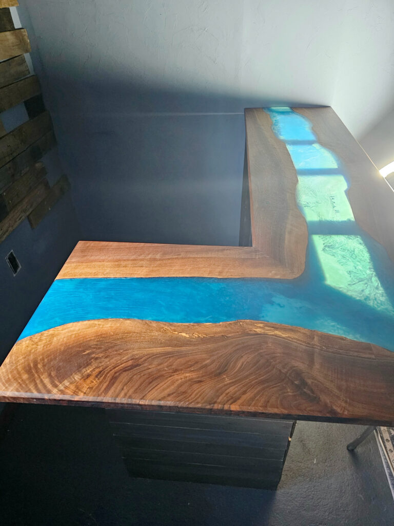 Custom Live-Edge Epoxy Bar 4 L-shaped black walnut live-edge bar top with a blue epoxy river catching the light