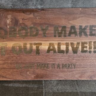 Solid walnut sign engraved with "Nobody Makes It Out Alive!! We just make it a party" in dripping lettering filled with glow-in-the-dark epoxy